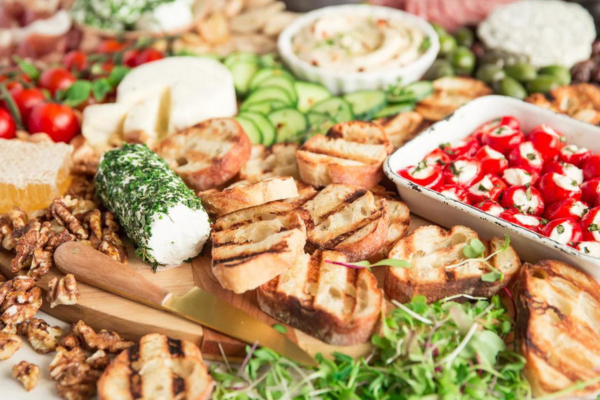 Close up of a cheese board filled with veggies, chips, nuts, and cheese