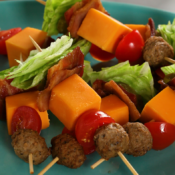 Meat, cheese, and lettuce skewers stacked on a green plate