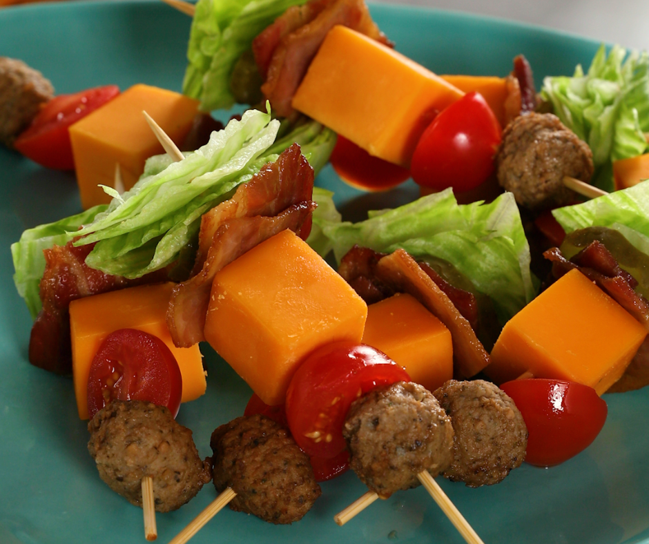 Meat, cheese, and lettuce skewers stacked on a green plate