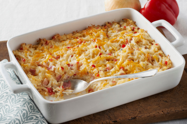 Close up image of a white casserole dish with baked hash brown casserole inside