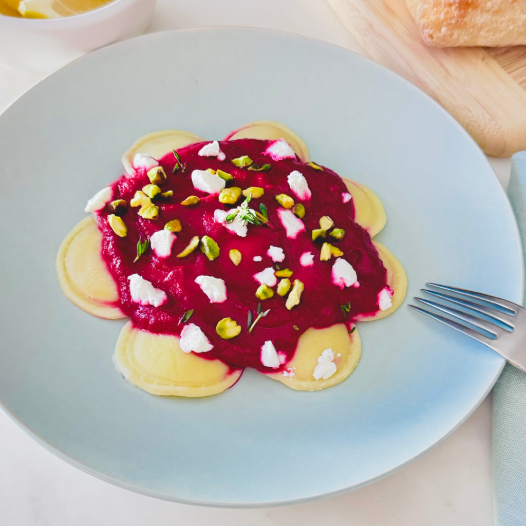 A bowl of raviolis with beet sauce