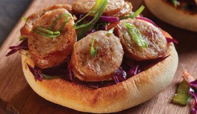 Close up of an english muffin topped with brats and herbs