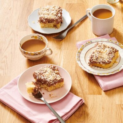 two cups of coffee and 3 plates of brown butter coconut snacking cake spread out