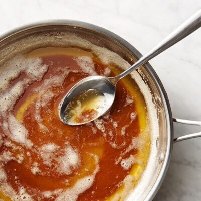 Overhead shot of a pan filled with brown butter with a spoon inside