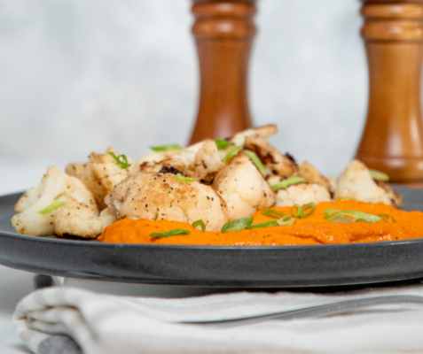 cauliflower and red sauce on a black plate