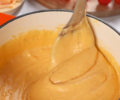 cheddar fondue in a pot being stirred