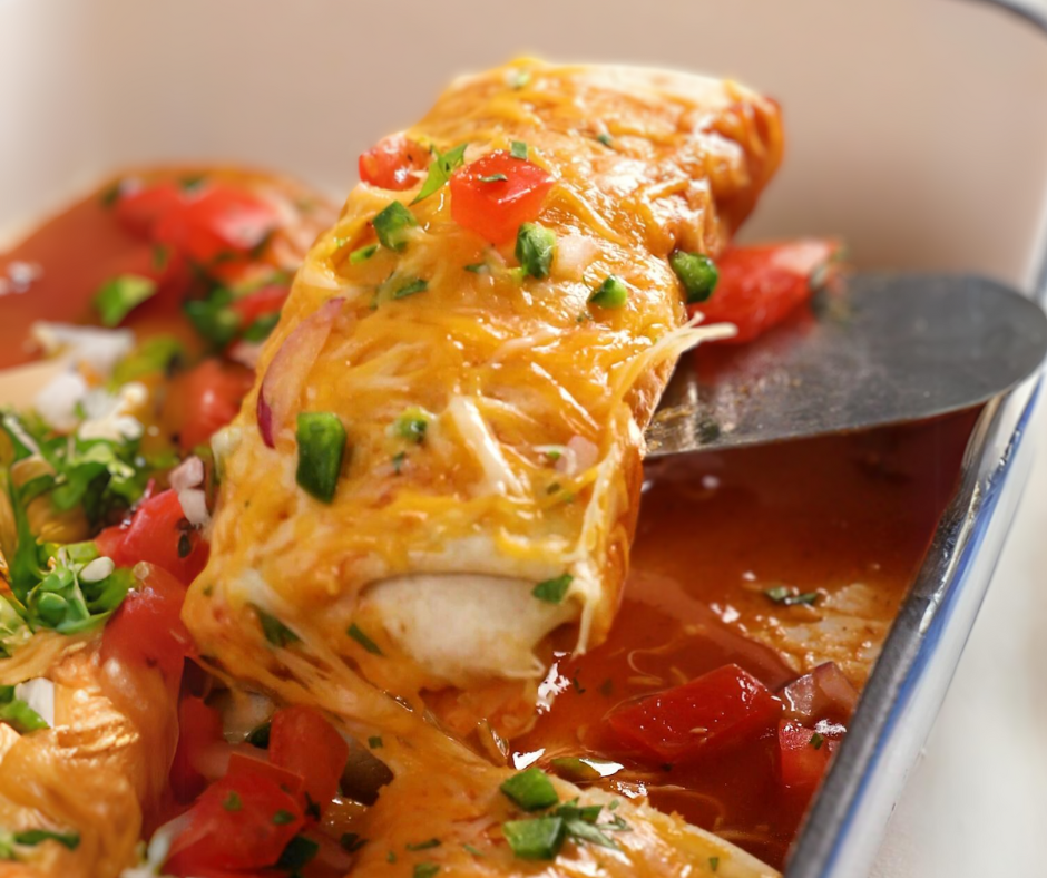 a cheese covered burrito being scooped out of a casserole dish