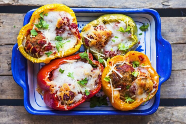 Four stuffed peppers in a blue casserole dish