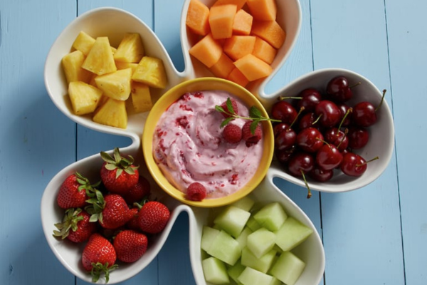 Overhead shot of a flower shaped bowl full of fruit and Creamy Raspberry Fruit Dip