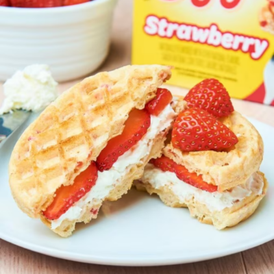 a waffle sandwich filled with strawberries and cream that has been cut in half and stacked on a plate