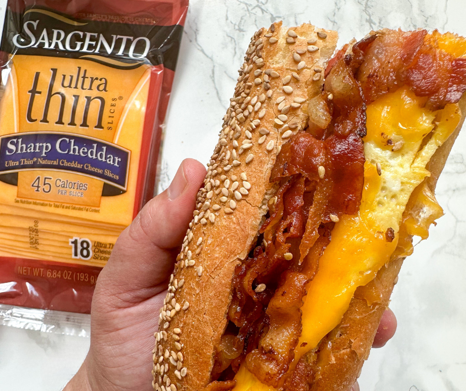 Close up of a hand holding a hoagie filled with bacon, egg, and cheese