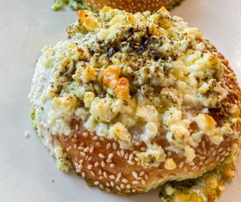 Close up of a bagel topped with egg, feta cheese and herbs