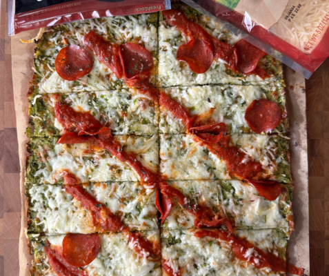 Overhead shot of a pepperoni pizza with green colored broccoli crust