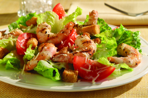 Close up of grilled shrimp caesar salad on a white plate