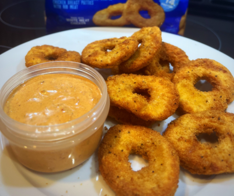 Plate with a cup of orange sauce and circular chicken nugget rings