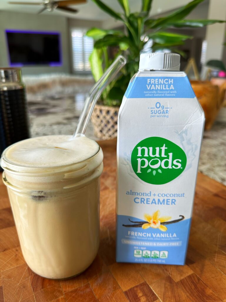 French Vanilla Cookie Butter Iced Latte in a glass with a straw next to a bottle of French Vanilla Nutpods Creamer