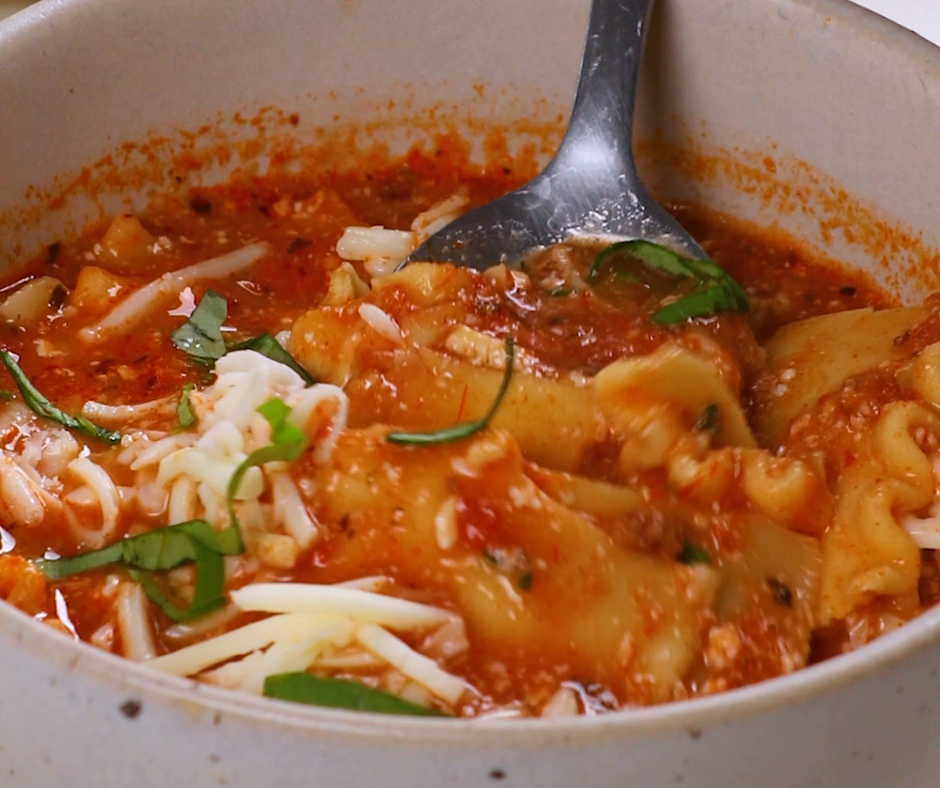 A small silver spoon mixing a bowl of lasagna soup