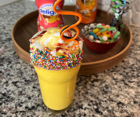 A glass with a sprinkles rim filled with mango lassi