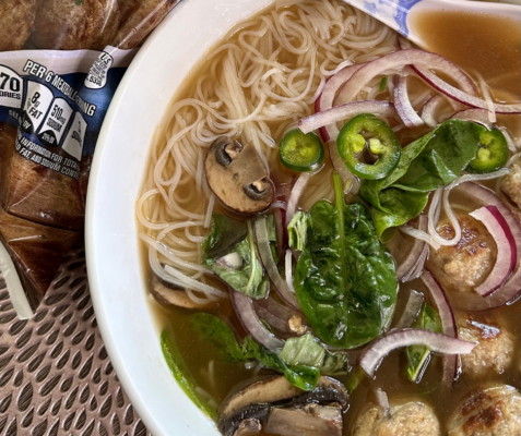 Overhead close up shot of a bowl of soup topped with jalapenos, mushrooms, spinach, and onions