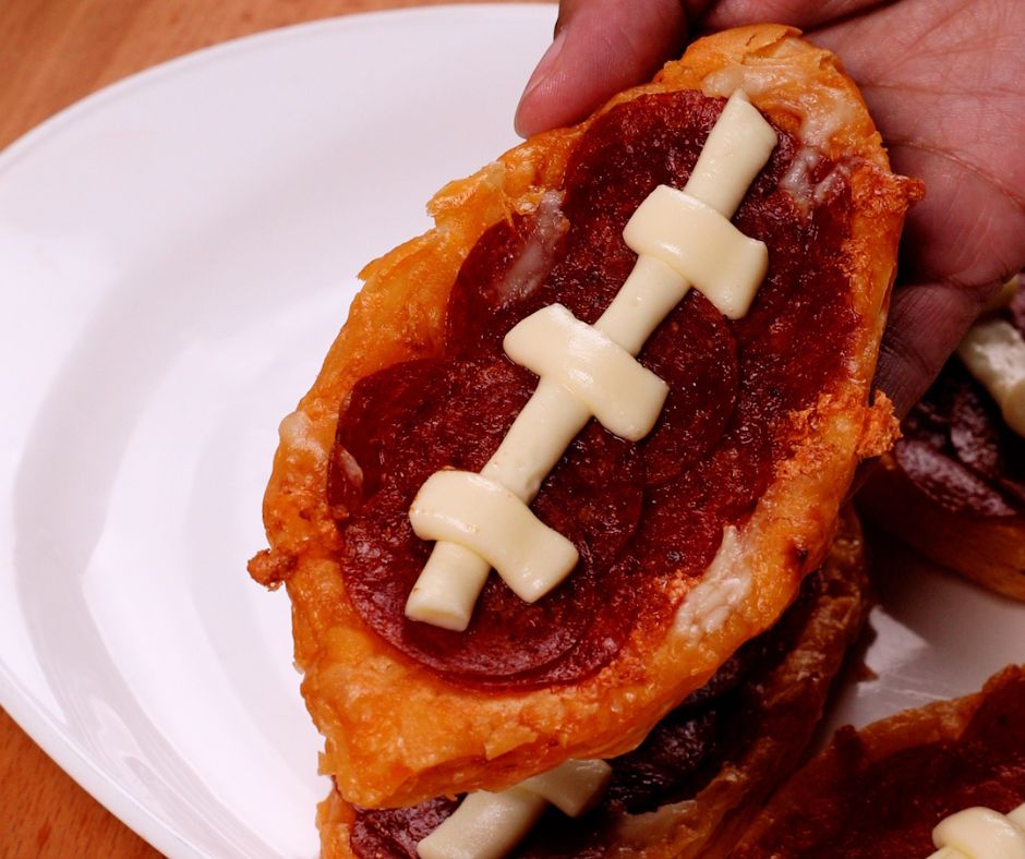 hand holding a mini football pizza