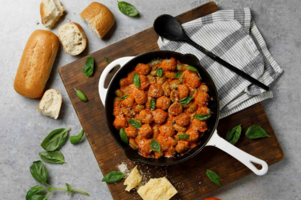 Pan filled with meatballs sitting on a wooden chopping block