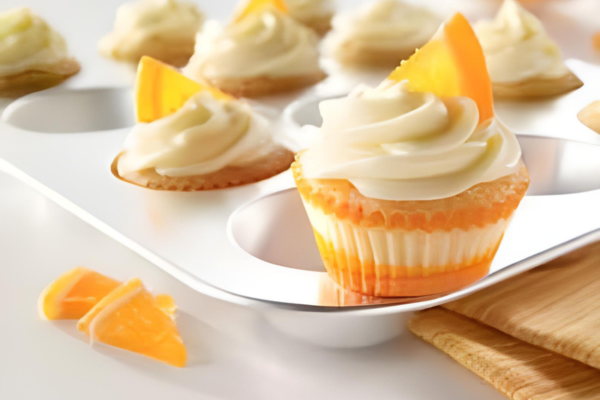 Gluten-free Orange Petite Cakes sitting in a muffin baking sheet 