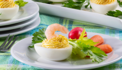 a single deviled egg on a white plate next to mixed greens