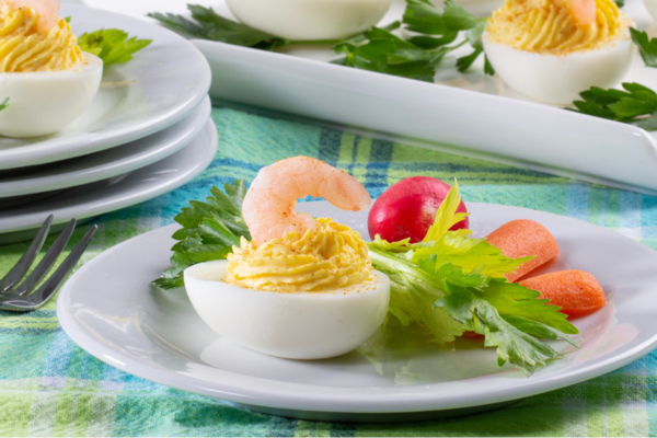 a single deviled egg on a white plate next to mixed greens
