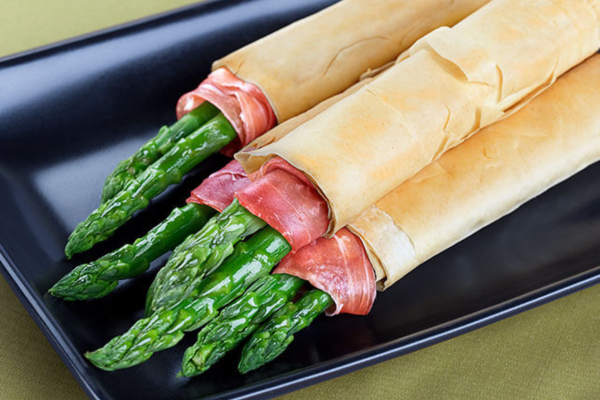 Multiple asparagus stems wrapped in prosciutto and phyllo dough