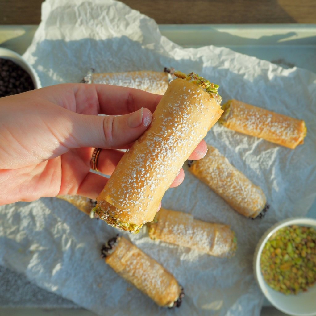 a hand holding a phyllo dough cannoli