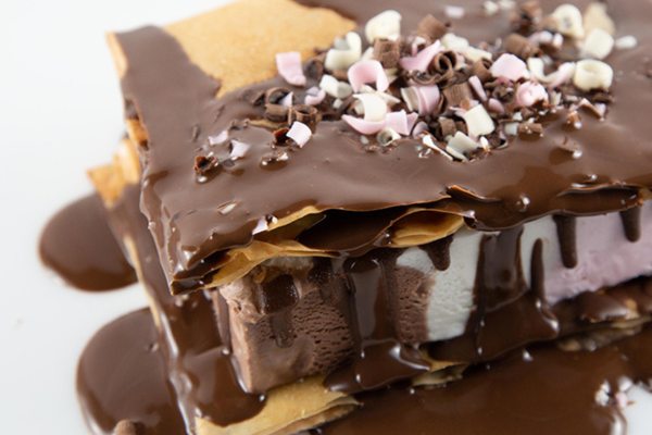 close up shot of smores ice cream sandwich covered with chocolate and shredded white chocolate pieces