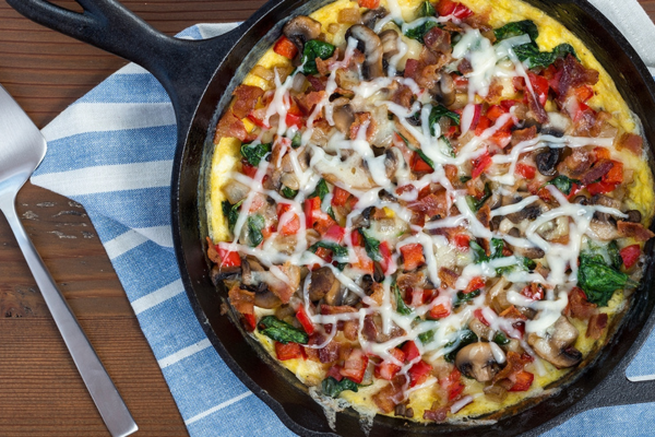 Overhead shot of FARMHOUSE BACON SWISS FRITTATA in a black skillet