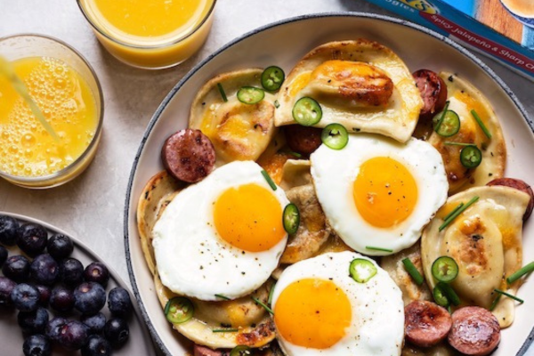 Pierogi and Kielbasa Skillet with a bowl of blueberries to the left and two glasses of orange juice