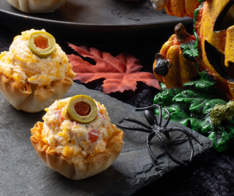 Two puff pastries filled with cheese spread next to a fake spider