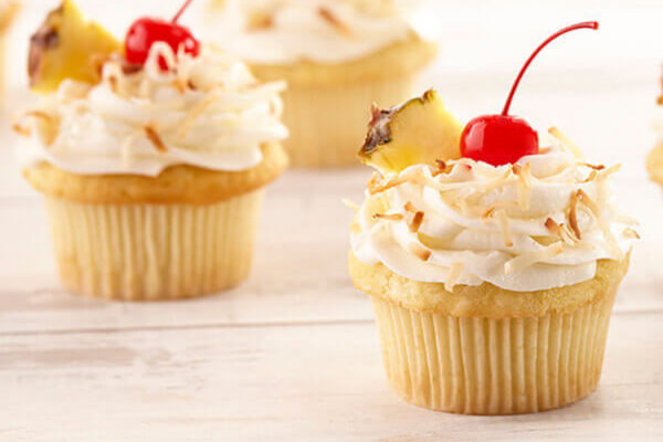 Close up shot of a pina colada cupcake with an out of focus pina colada cupcake behind it