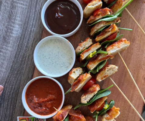 kabobs next to three dipping sauces