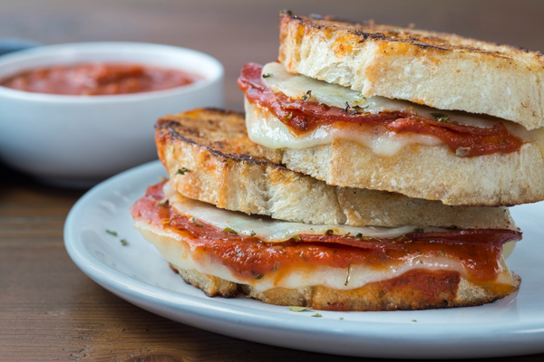 Close up of two grilled cheese sandwiches stacked on a white plate