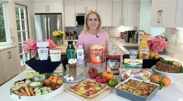 Chef Jamie Gwen in a kitchen standing in front of an assortment of dairy aisle foods