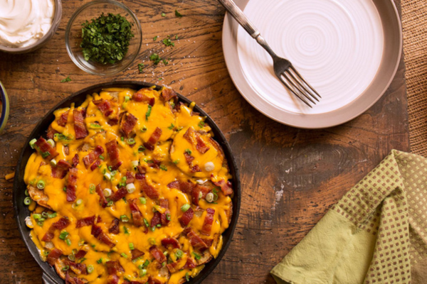 overhead image of pub style nachos in a black skillet and a white plate with a fork next to it