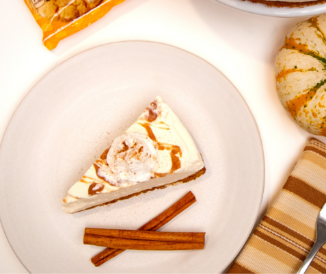 Overhead shot of a slice of cheesecake and 2 cinnamon sticks on a plate