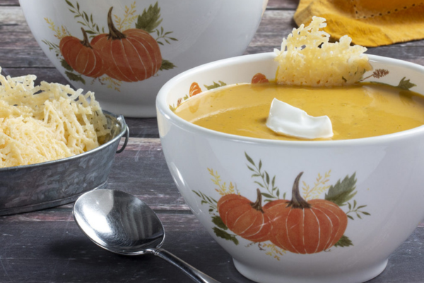 white bowl decorated with pumpkin design filled with butternut squash soup