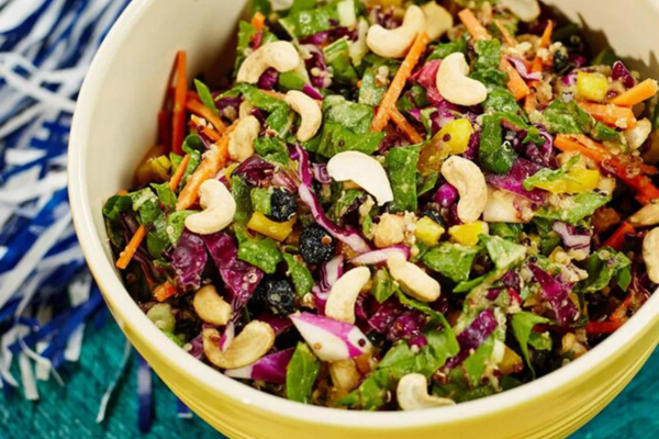 Close up overhead photo of a yellow bowl filled with rainbow chopped cashew salad