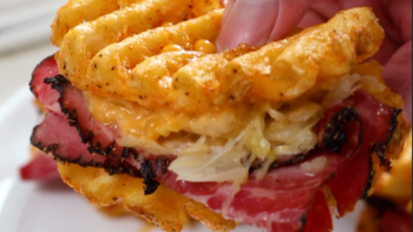 Hand holding a waffle fry Reuben slider