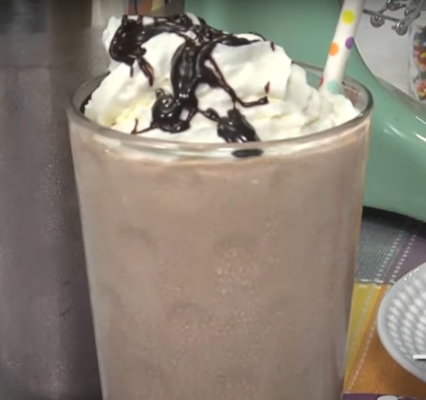 Thick Frosty Shake in front of a piece of pie topped with ice cream on a white plate