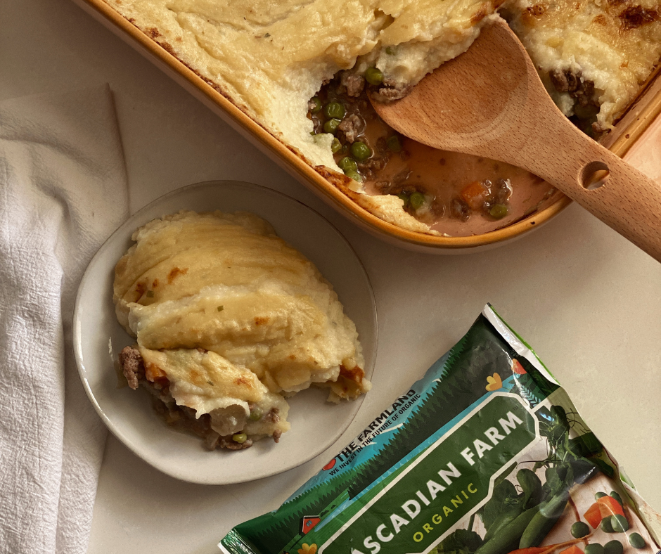 Overhead shot of a dish with a piece of shepherd's pie on it next to a pan of shepherd's pie