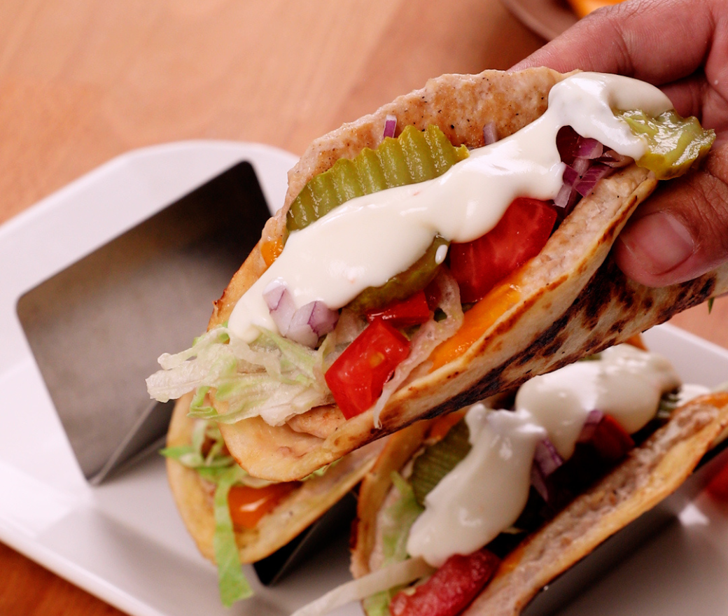 A hand holding a smashburger chicken taco