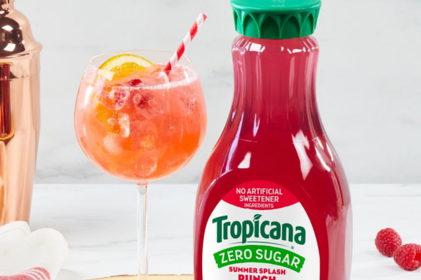 an orange beverage in a cocktail glass next to a bottle of tropicana zero sugar summer splash punch