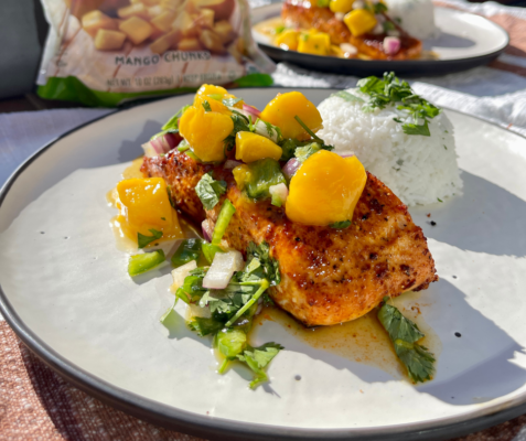 Cooked salmon topped with fruit salsa on a white plate