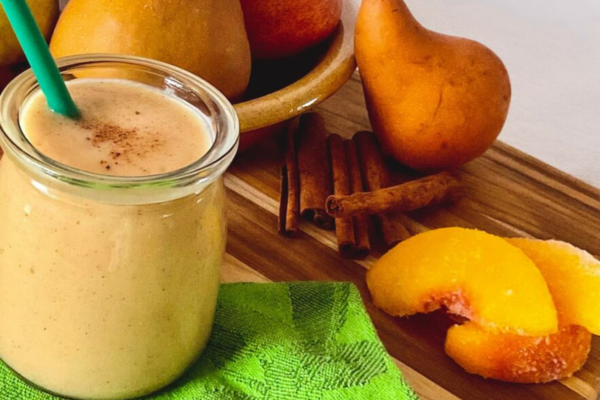 Close up of a peach and pear smoothie next to pears and cinnamon