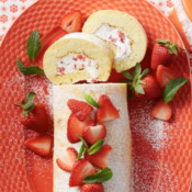 strawberry cream roll topped with strawberries sitting on a red plate